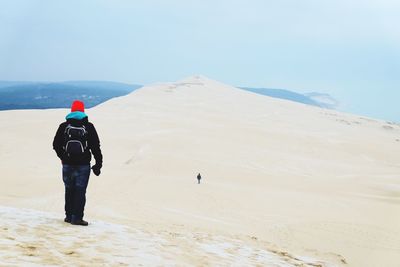 Rear view of man standing at desert during winter