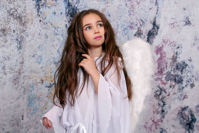 Portrait of beautiful young woman standing against wall