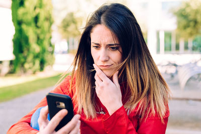 Close-up of thoughtful woman using mobile phone in garden