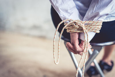 Low section of woman hands tied with rope