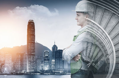 Side view of man looking at city buildings against sky