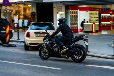 Side view of man riding motor scooter on street