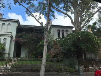 Low angle view of house and trees by building against sky