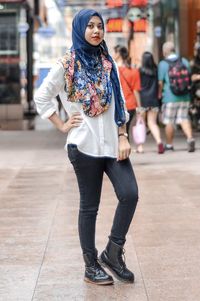 Full length portrait of young woman on street in city