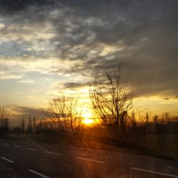 Road amidst bare trees against sky during sunset