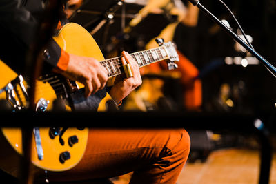 Midsection of man playing guitar on stage