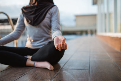 Low section of woman sitting on hardwood floor