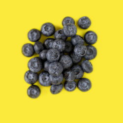 Directly above shot of blueberries in plate against yellow background