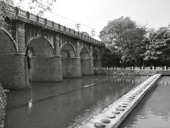 Arch bridge over river against sky