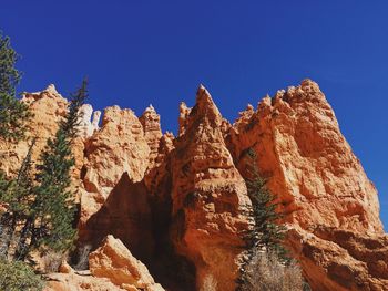 Low angle view of rock formation against clear blue sky