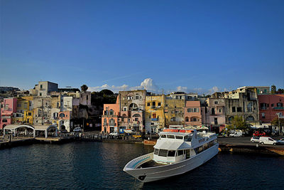 Boats in sea against clear blue sky