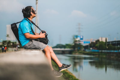 Man sitting on boat in lake against sky