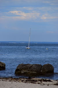 Sailboat on rock in sea against sky