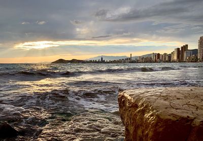 Scenic view of sea and buildings against sky during sunset