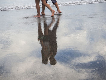 Low section of people walking on beach