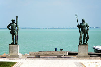 Statue by sea against clear sky