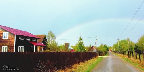 Road amidst houses and buildings against sky