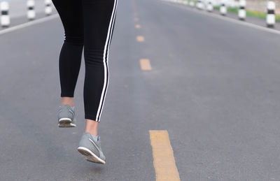 Low section of woman walking on road