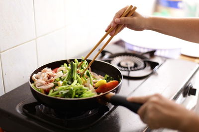 Midsection of person preparing food in kitchen at home