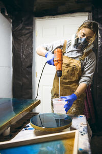 Female resin artist mixing with respirator mask