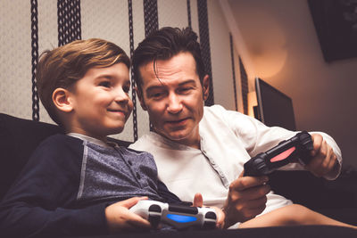 Father and son playing video game at home