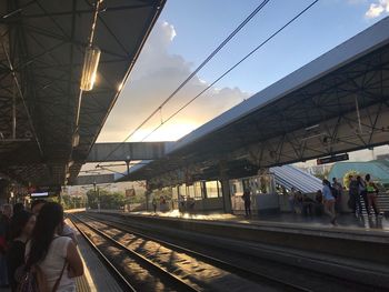 People waiting at railroad station platform against sky