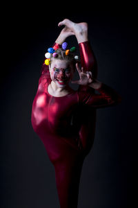 Portrait of woman wearing clown costume against black background