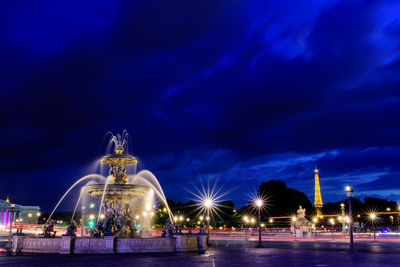 Illuminated fountain against blue sky at night