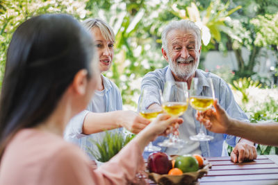 Smiling friends toasting wineglasses while sitting at table