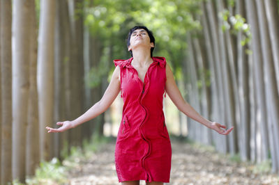 Woman with arms outstretched standing amidst trees