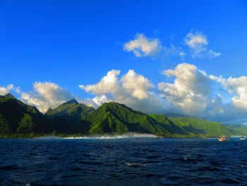 Scenic view of sea and mountains against blue sky