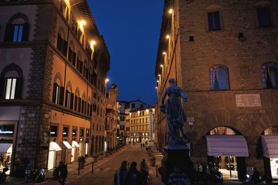 Illuminated street amidst buildings in city at night