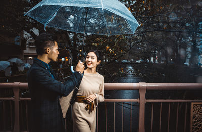 Young couple standing on railing during rain