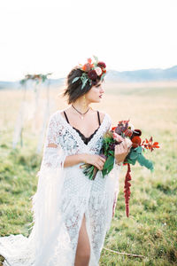 Young woman with flower bouquet in field