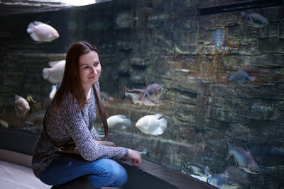 Smiling woman looking at fishes in aquarium