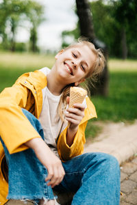 Portrait of a cute blonde teenage girl with ice cream on a walk in the park. child outdoors