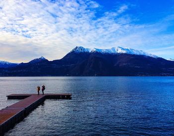 Friends standing on pier over lake