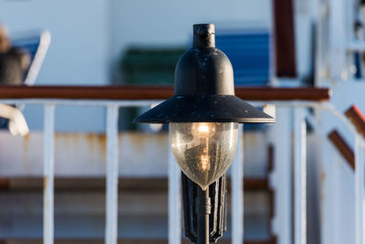 Close-up of illuminated lamp on railing against building