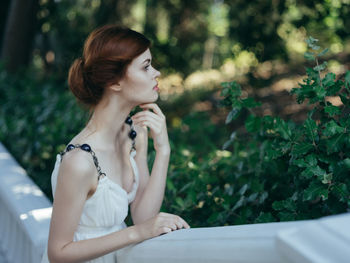 Young woman looking away while sitting on plant