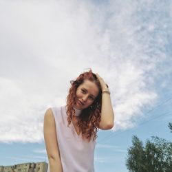 Low angle view of young woman standing against sky