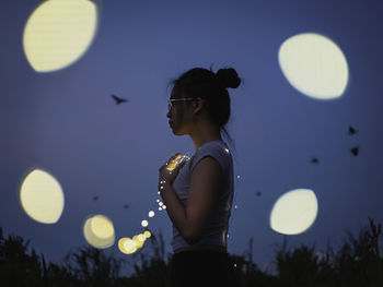 Side view of woman standing at night