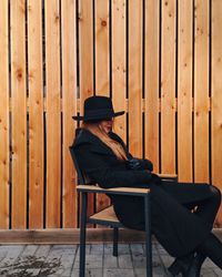 Girl sitting on chair against wall