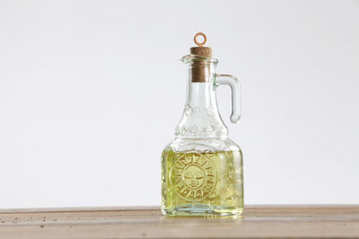 Close-up of olive oil in jar on table against white background