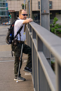 Rear view of man standing by railing in city