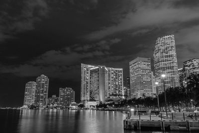 Low angle view of illuminated city against cloudy sky