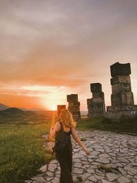 Back view of woman standing at memorial at sunset