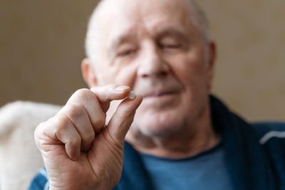 Close up view of senior male hand holding pill and taking it