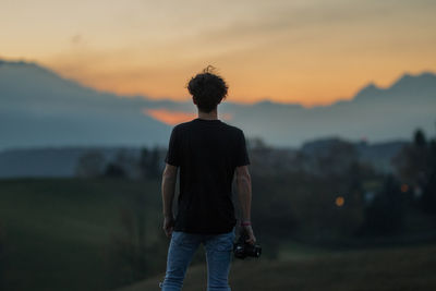 Rear view of man standing against sky during sunset