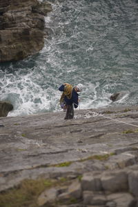 Rear view of man standing on rock in sea