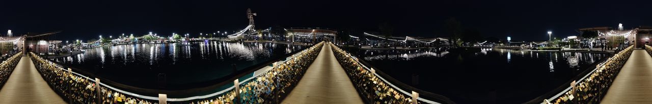 Panoramic shot of illuminated bridge over canal in city at night